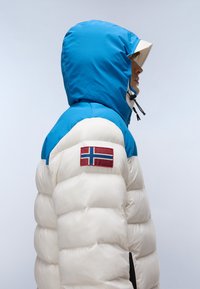 Puffjacka med en blå huva och vit kropp, med horisontell vaddning. Inkluderar en Norge-flagg patch på axeln.