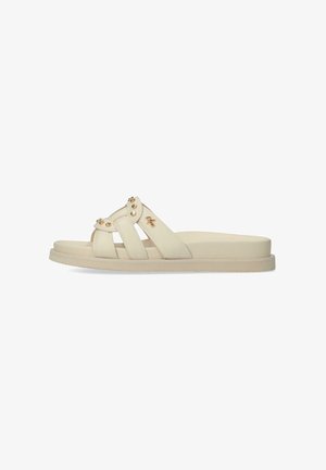 Light beige slide sandals made of smooth synthetic material, featuring two broad straps and decorative gold-tone accents. Flat sole design.