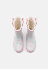 Bottes de pluie pour enfants rose et blanche avec une doublure en fausse fourrure douce, un extérieur en caoutchouc lisse et des motifs de cœurs bleus et roses.