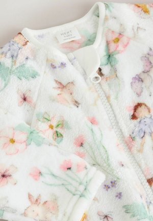 Fleece babypakje met een witte achtergrond, voorzien van kleurrijke bloemen- en dierenpatronen. Ritsluiting en geribbelde halslijn. Zachte textuur.
