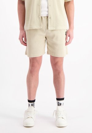 Helle beige Shorts aus strukturiertem Stoff mit einem elastischen Bund und seitlichen Taschen, kombiniert mit einem passenden kurzärmligen Oberteil.