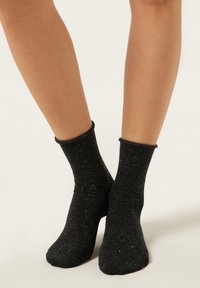 Black ankle socks with a textured pattern and soft, stretchy material. Cuffs are ribbed, providing a secure fit around the ankles.
