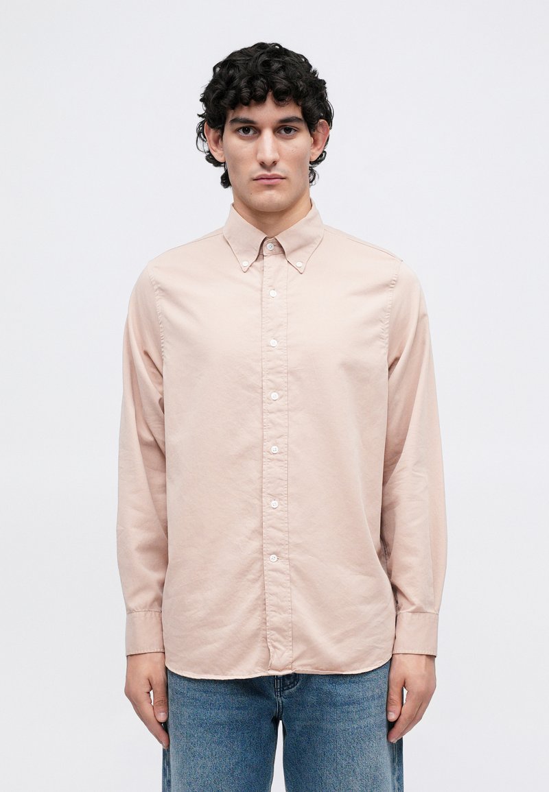 Lichtroze langemouwen shirt met een button-down kraag, met een gladde textuur en witte knopen, gecombineerd met blauwe denim jeans.