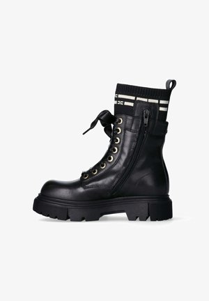 Stivale alla caviglia in pelle nera con suola in gomma, occhielli dorati e cerniera laterale. Presenta un bordo in maglia nera con strisce bianche e un fiocco.