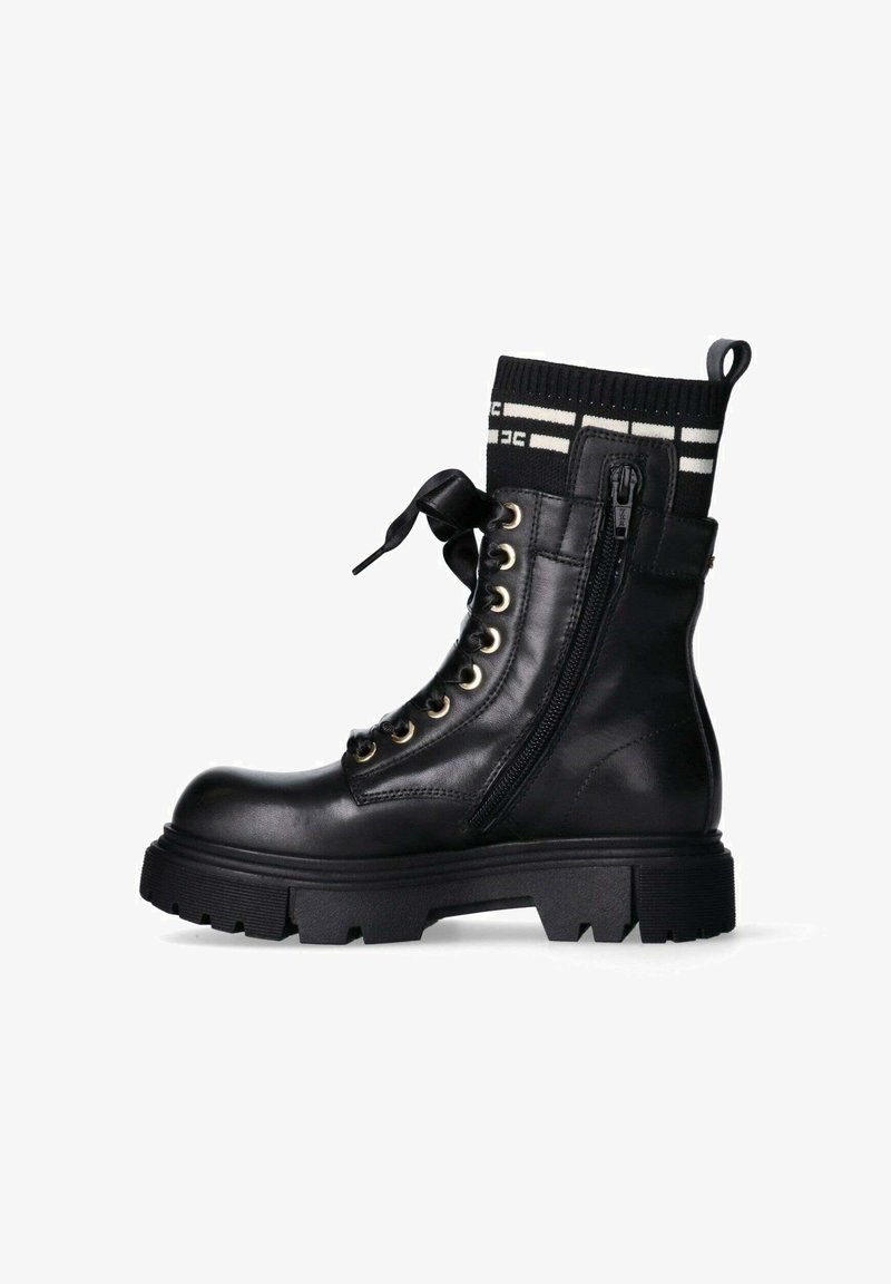 Stivale alla caviglia in pelle nera con suola in gomma, occhielli dorati e cerniera laterale. Presenta un bordo in maglia nera con strisce bianche e un fiocco.