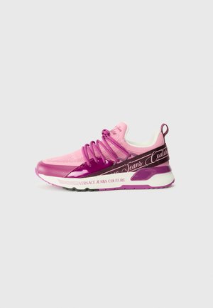 Sapatilhas Versace com um cabedal em malha rosa, detalhes brilhantes em roxo e a marca "Versace Jeans Couture" em uma sola preta texturizada.