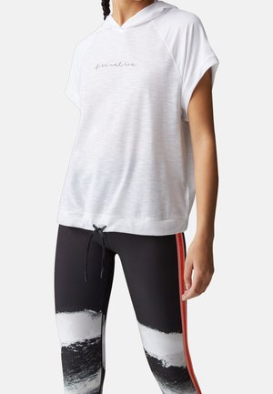 Kvinde iført en hvid kortærmet hættetrøje med teksten "fire and ice" kombineret med sorte leggings med et mønster af hvide og sorte penselstrøg samt røde striber.