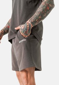 Grijze katoenen shorts met zijzakken, voorzien van een relaxed fit en een klein wit logo op de voorkant. Soepele textuur, casual ontwerp.