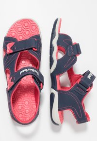 Navy blue sandals with pink accents, featuring Velcro straps, hexagonal-patterned insoles, and a white rubber sole. Durable materials used.