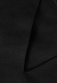Tissu noir avec une texture lisse et mate, doté d'un bord replié, indiquant une forme structurée. Aucune motif ou embellissement visible.