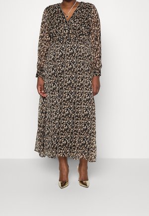Woman wearing a long-sleeve, ankle-length black and beige abstract print dress with gold pointed-toe heels and a pendant necklace.