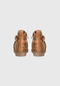 Smeđe čizme do gležnja s uzorkom u leopard printu i detaljem kopče, pogledane iz pozadine na jednostavnoj bijeloj pozadini.
