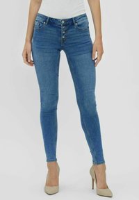 Faded blue denim jeans with a high waist, five-button closure, and a skinny fit. Features front pockets and a smooth texture.