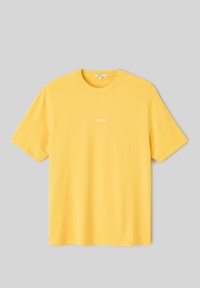 T-shirt jaune en coton à manches courtes avec petit texte blanc « CAPELINNE » centré sur la poitrine, col rond, présenté à plat sur fond gris.