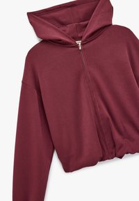 Bordeaux zip-hoodie med stor hætte, lange ærmer og en afslappet pasform. Fremstillet af blødt, glat stof uden synlige mønstre eller hardware.