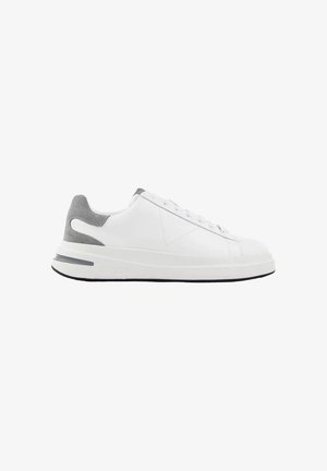 Zapatilla deportiva blanca de corte bajo con parche en el talón de ante gris, cordones blancos y una suela blanca gruesa con detalles en gris y negro.