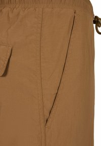 Bruine stoffen shorts met een elastische tailleband, een trekkoord en zijzakken met subtiele stikseldetails. De textuur lijkt licht van gewicht.