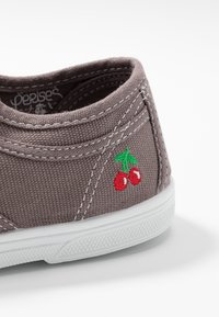Sneaker in tela grigia con suola in gomma bianca. Presenta un design di ciliegie ricamate in verde e rosso. Cuciture in vista e tessuto testurizzato.