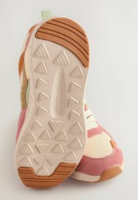 Buty sportowe z teksturowaną gumową podeszwą z trójkątnymi wytłoczeniami, z połączenia różowych, kremowych i brązowych materiałów oraz płaskimi bawełnianymi sznurowadłami.