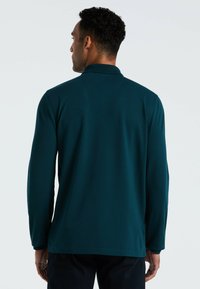 Langsleeve polo-shirt in donker teal, gemaakt van een gladde stof met een klassieke kraag. Heeft een rechte snit en minimale stikdetails.