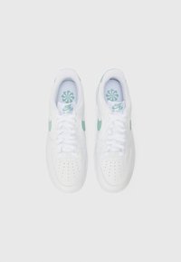 Bijele Nike Air Force 1 tenisice s svijetlozelenim Swooshom i uloškom, perforiranim prstom i ravnim vezicama. Gornji dio od glatke kože.