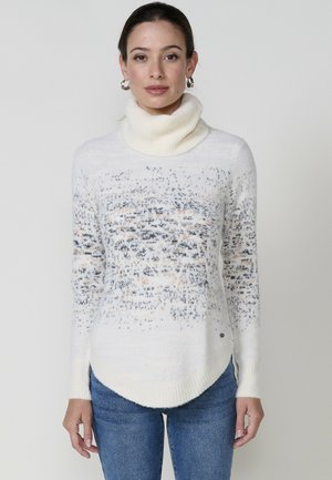 Jersey de cuello alto blanco con un patrón degradado de puntos en azul claro y melocotón. Textura suave, mangas largas y diseño de dobladillo redondeado.