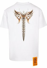 Hvid bomulds T-shirt med et intrikat brunt og orange rygdesign, samt en orange etiket i kanten, der viser mærket.