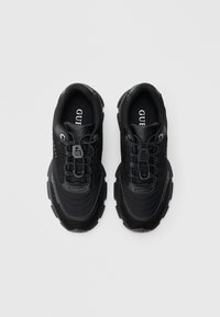 Ζευγάρι μαύρα αθλητικά παπούτσια GUESS με χοντρές σόλες, πάνελ από δίχτυ και δέρμα, ελαστικές κορδόνια και εμφανές λογότυπο της μάρκας στη γλώσσα και στην εσωτερική σόλα.