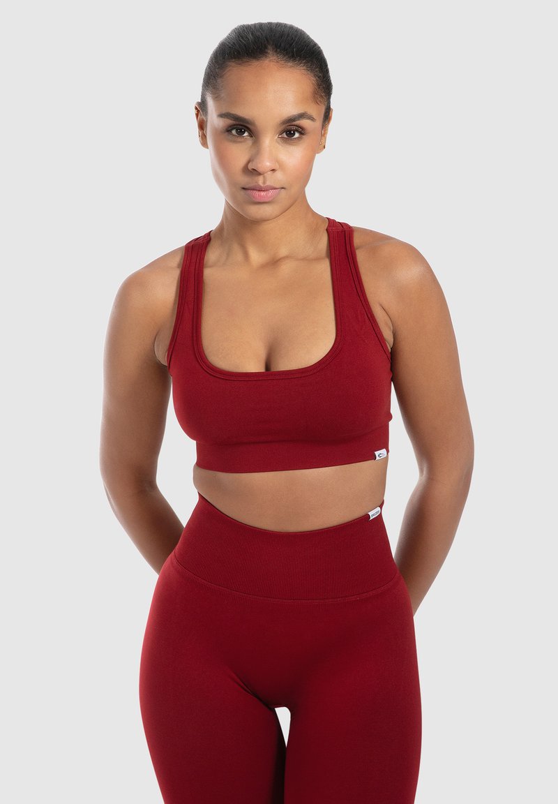 Červený sportovní crop top s širokými ramínky a žebrovanou strukturou, který je spárován s vysokými legínami ve stejném stylu. Hladký, přiléhavý design.