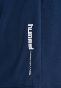 Marina sportshorts i mjukt tyg, med en vertikal vit "hummel" logotyp och texten "PERFORMANCE" på sidan.