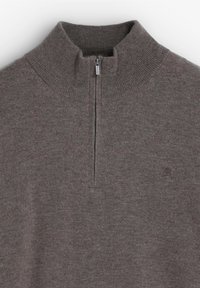 Pulóver gris, texturizado, con un cuello alto, cierre de media cremallera y un pequeño detalle del logo en la parte inferior derecha.