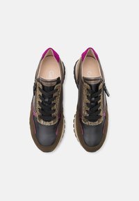 Paire de baskets basses décontractées avec des panneaux noirs, marron, or et violet, lacets noirs et fermetures éclair latérales, vues de dessus sur fond blanc.