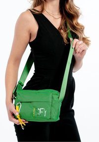 Borsa a tracolla verde realizzata in materiale a rete testurizzata, con chiusura con zip, una tracolla robusta e dettagli in metallo giallo.