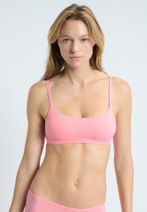 Bra sportivo rosa con spalline sottili, texture liscia e design minimalista. Presenta un scollo dritto e basso e una silhouette semplice.