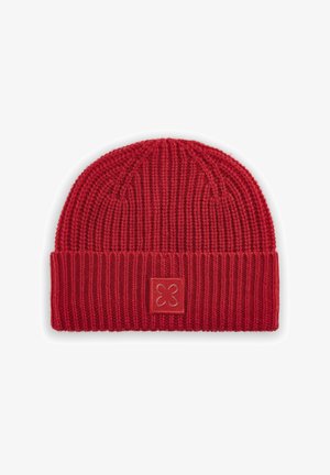 Beanie rouge en tricot avec une texture côtelée, un revers replié et une étiquette en cuir carrée présentant un motif floral sur le devant.