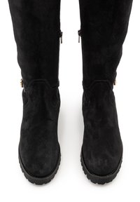 Schwarze kniehohe Stiefel aus Wildleder mit glatter Textur, ausgestattet mit goldfarbenen Reißverschlüssen an den Außenseiten und einer robusten Sohlenkonstruktion.