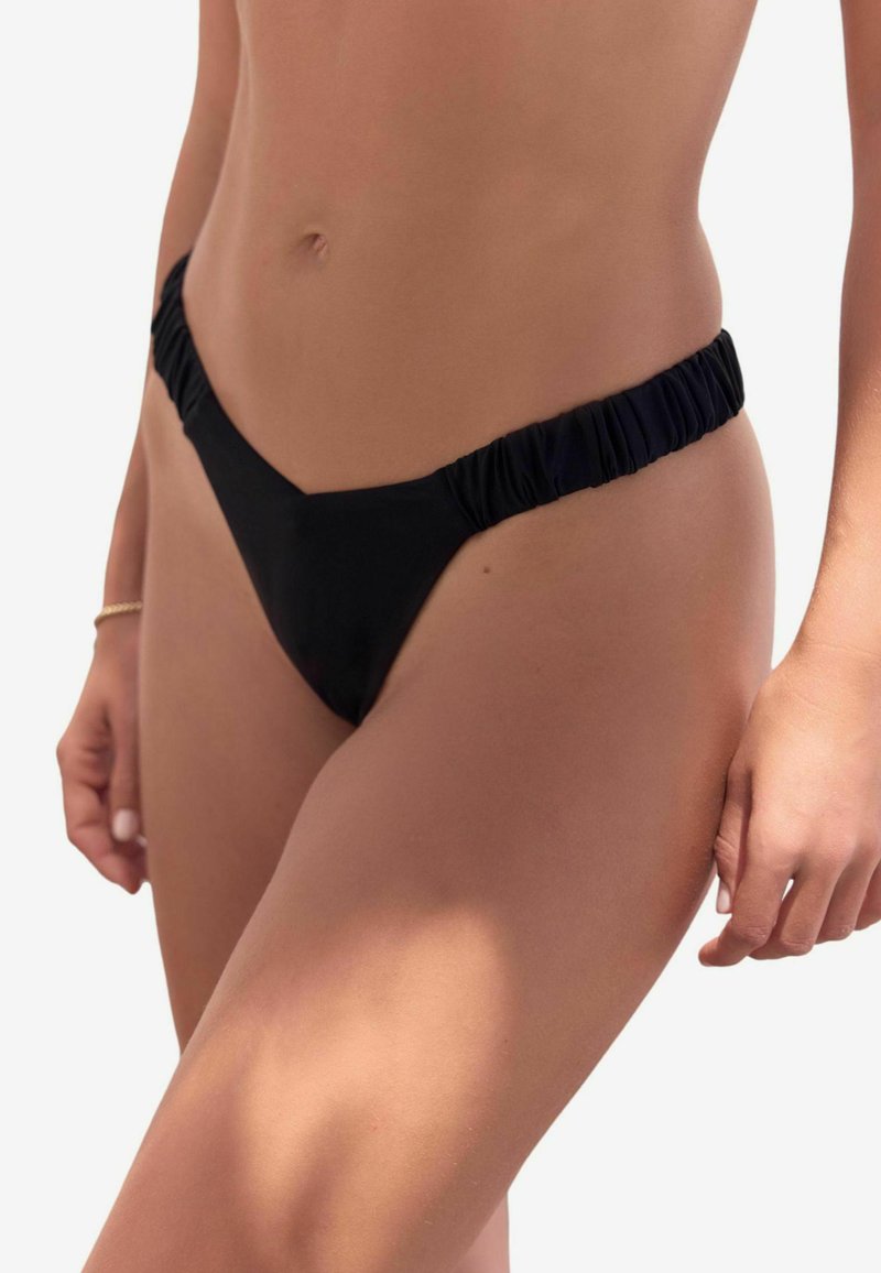 Svart bikiniunderdel med V-form, med samlade sidor. Tyget verkar slätt och elastiskt, designat för komfort och passform.