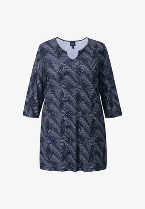 Marineblauw tuniek met een getande halslijn, driekwartmouwen en een patroon van witte stippen en golvende lijnen. Zachte, lichte stof.