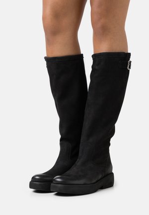Bottes montantes noires en daim texturé, avec un bout lisse, un design minimaliste et une boucle latérale en accent.