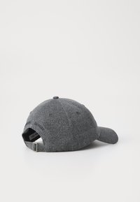 Grå baseball caps laget av vevd stoff. Har en buet skygge, justerbar stropp bak og brodert tekst på siden.