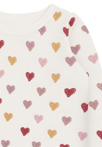 Weißer Stoff mit verstreuten, handgezeichneten Herzen in Rot, Rosa, Mauve und Senfgelb auf einem Langarmkleidungsstück.