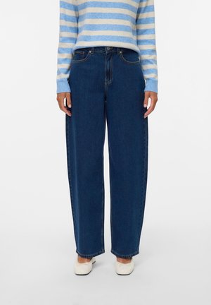 Jeans in denim blu a gamba larga con vita alta, caratterizzati da un classico design a cinque tasche e dettagli di cucitura. Indossati con un maglione blu a righe.