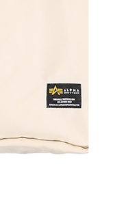 Beige szövet sima textúrával, fekete címkével, fehér és sárga szöveggel, emblémával és varrás részletekkel.