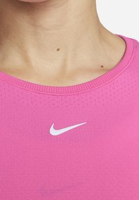 Top atletico rosa con scollatura rotonda, realizzato in tessuto testurizzato, con un piccolo logo Nike bianco sul petto.