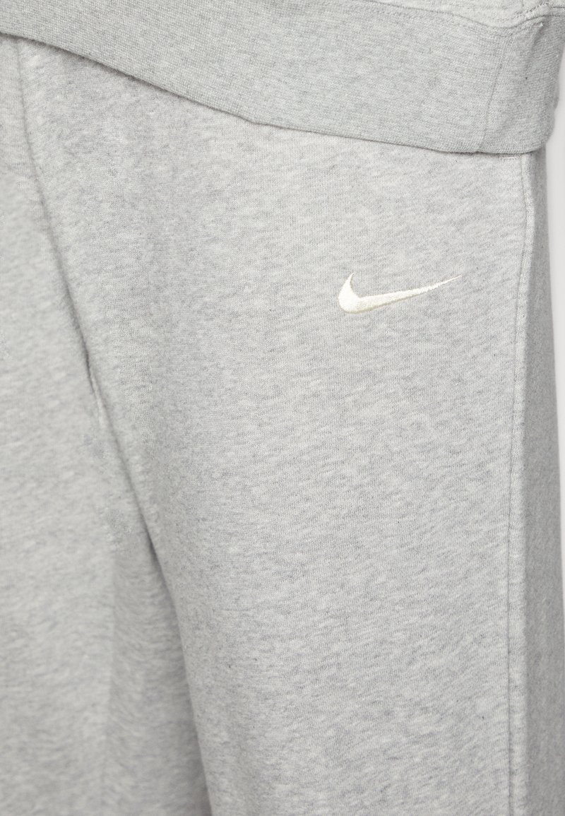 Graue Sweatpants aus weichem Material, mit einem kleinen weißen Nike-Logo am linken Bein und einem bequemen elastischen Bund.