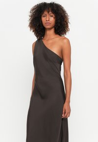 Robe marron à une épaule en tissu lisse avec un design fluide et un détail froncé sur le côté. Idéale pour des occasions formelles ou des soirées.