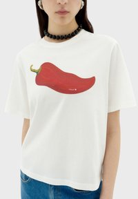 Witte katoenen t-shirt met een grote rode chilipeperafbeelding. Korte mouwen, ronde hals, relaxte pasvorm en een gladde textuur.