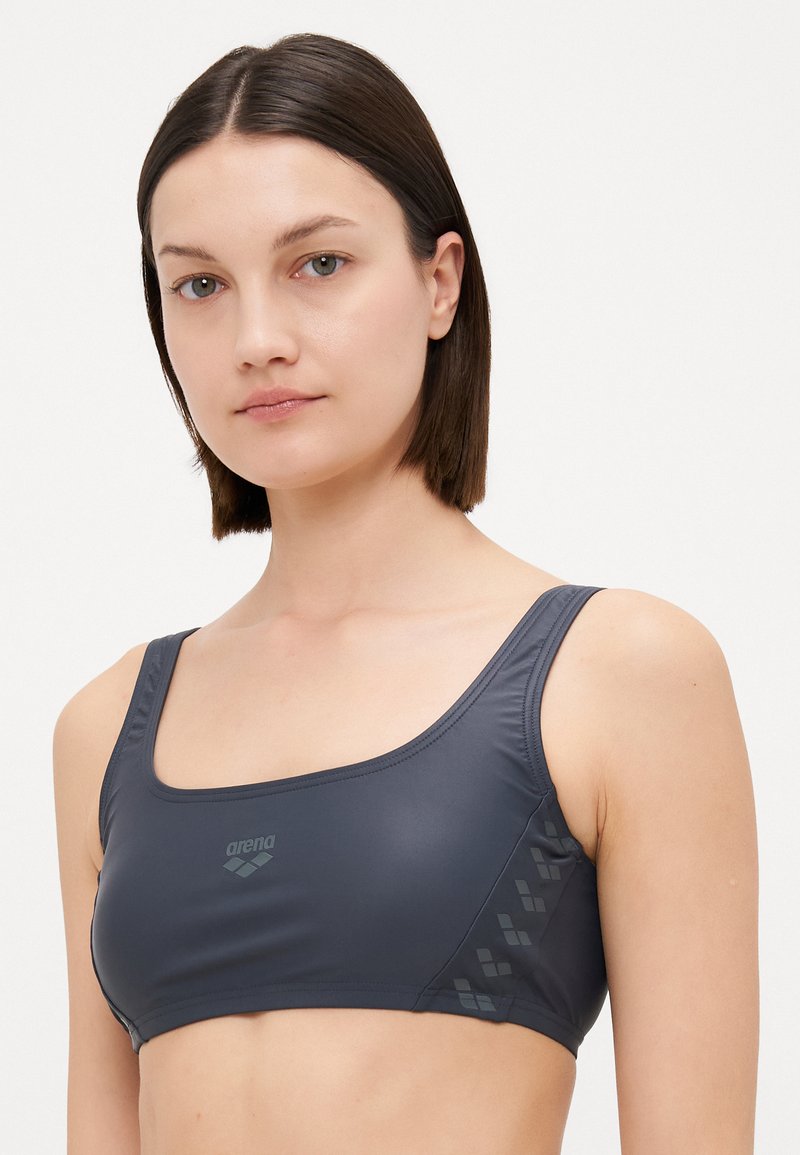 Grauer sportlicher Bikini-Oberteil mit quadratischem Ausschnitt und breiten Trägern. Verfügt über ein strukturiertes Muster an den Seiten und ein kleines Logo auf der Vorderseite.