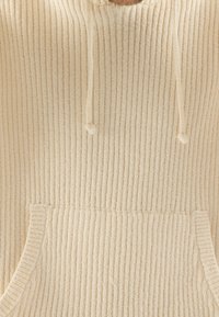Cremefarbener gerippter Hoodie aus strukturiertem Stoff, mit einer vorderen Tasche und Kordeln für eine verstellbare Passform.