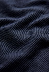 Tmavě modrá nabořena tkanina s texturovaným povrchem, vykazující jemné horizontální linie a subtilní odchylky ve stínu.